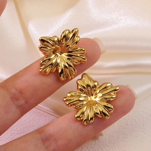 Élégantes boucles d'oreilles fleur en titane doré sur fond de texture soie