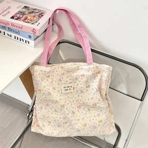 Detail of quilted canvas tote bag with floral puppy prints and pink handles on a chair