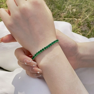 Detailed view of 4mm green zircon tennis bracelet on wrist with a silver-plated setting