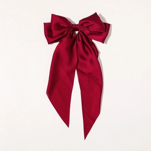 Close-up of elegant red satin oversized bow hair clip with long flowing ribbons