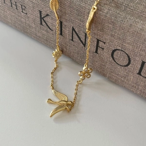 925 sterling silver gold necklace with swallow, flower and leaf pendants on a book