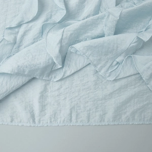 Close-up of light blue textured fabric showing ruffled layers and fine stitching details