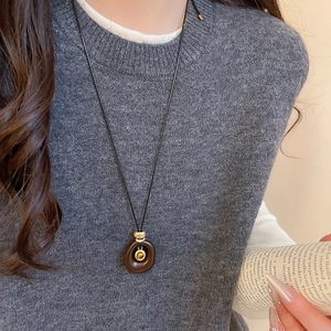 Nahaufnahme einer Vintage-Halskette mit braunem Harzring und Tigerauge am Model