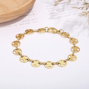 Detail of gold coin chain link bracelet with lobster clasp on elegant prop background