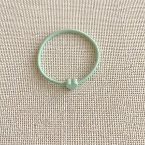 Dettaglio dell'elastico per capelli verde menta con ciondolo a forma di cuore opaco