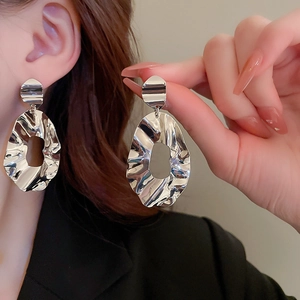 Detail of silver irregular crumpled earrings showing liquid metal texture on ear