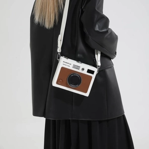 Close-up of a white and brown vintage camera-shaped shoulder bag featuring detailed leather texture