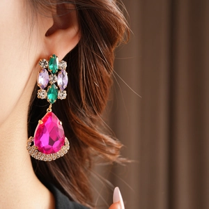 Close-up of vintage gold earrings with emerald and rose red crystals on model