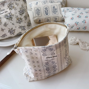 Close-up of floral cotton pouch with simple wish label and golden makeup mirror