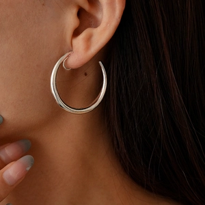 Close-up of minimalist silver geometric C-shaped clip-on hoop earring on model ear
