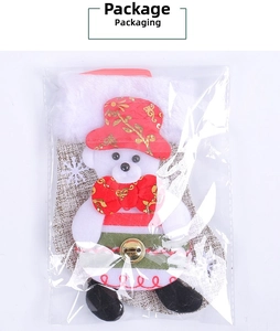 Detailed packaging of a plush Christmas bear ornament with festive red and gold accessories