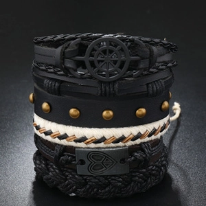 Detail of multi-layer braided leather bracelets with nautical charms and metal studs