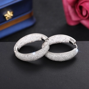 Macro detail of silver micro-pave hoop earrings with cubic zirconia on black leather