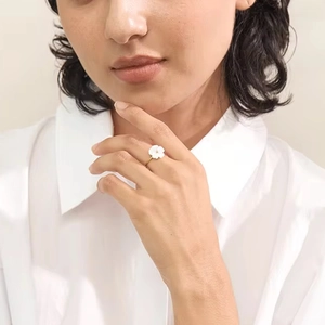 Elegance stainless steel golden ring with white flower charm on female model finger