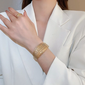 Close-up of golden multi-layer wrap ring and wide cuff bracelet set on a female model