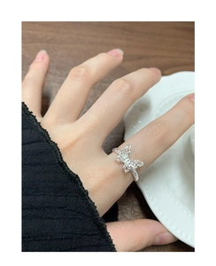 Detail of silver S925 butterfly ring with hollow texture worn on index finger
