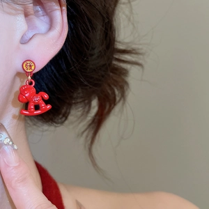Close-up of red rocking horse earring with gold Fu character on a female model's ear