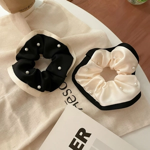 Elegante set de coleteros de seda en blanco y negro con perlas sobre fondo de lona