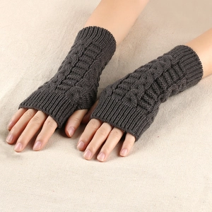 Close-up of dark brown cable knit fingerless gloves showing thick texture and warm wool