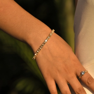 Detailed close-up of a golden tennis bracelet with rectangular-cut yellow zircons