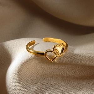 Macro detail of gold interlocking hearts on an adjustable open ring over satin fabric