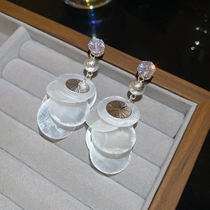 Detailed view of tassel earrings with zircon, silver studs, and layered shell textures