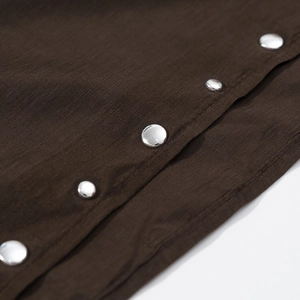 Close-up of silver metal snap buttons on dark brown textured fabric with horizontal lines