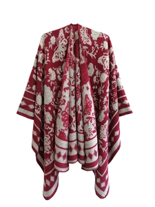 Close-up of bohemian red poncho shawl featuring cream jacquard floral patterns and tassel trim