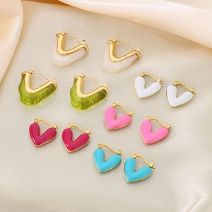 Macro shot of colorful V-shaped enamel earrings on champagne silk fabric background
