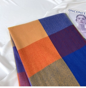 Detailed knit texture of a colorful plaid scarf in orange, blue, and purple tones