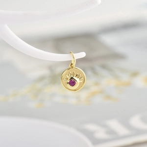 Golden evil eye coin pendant with pink zircon and radiant engraved sunbeam pattern