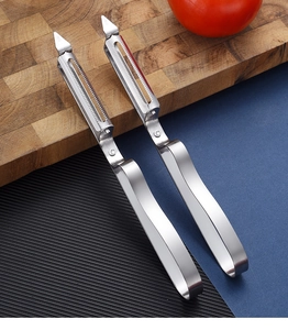Macro view of stainless steel vegetable peeler with serrated blade on wooden board