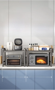 Detail of expandable dark grey metal microwave rack showing dual-tier storage space