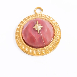 Detail of golden geometric star pendant with red agate stone and textured metal edges
