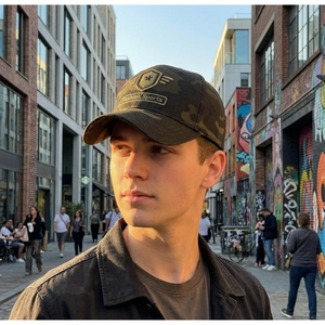 Close-up of camouflage baseball cap with detailed star embroidery on an outdoor street