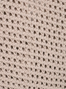 Close-up detail of the beige knitted vest featuring intricate hollow crochet pattern