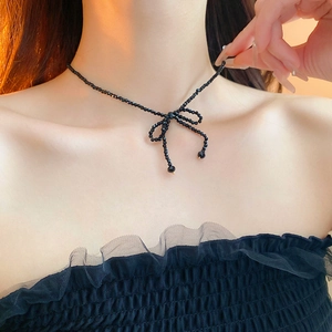 Close-up of black beaded bow choker necklace with gold details on a female model