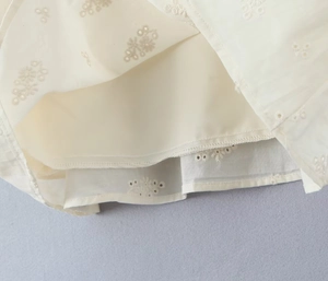Close-up of intricate lace embroidery and fabric texture on white puff sleeve dress