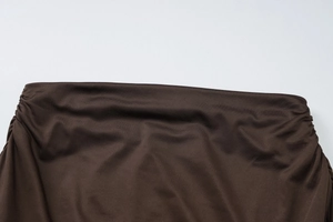 Détail du tissu froncé marron foncé montrant la texture plissée élégante et les coutures