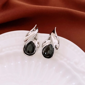 Macro shot of silver teardrop earrings with black pear-shaped crystals on ceramic plate