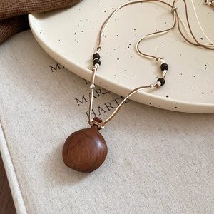 Close-up of vintage wood water-drop pendant with ethnic beads on a wax cord necklace