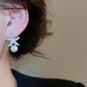 Détail de la boucle d'oreille étoile de mer avec pavé de zircons et perle blanche