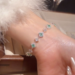 Close-up of elegant silver bracelet featuring square emerald gems and round zircons