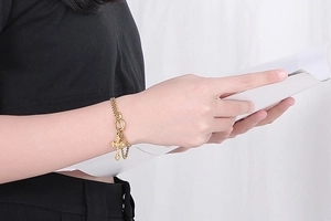 Close-up of golden double-strand bracelet with cross pendant and OT toggle clasp