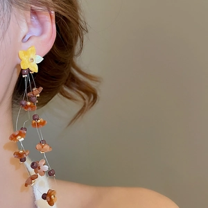 Detailed view of long tassel flower earrings with amber resin petals and pearl accents