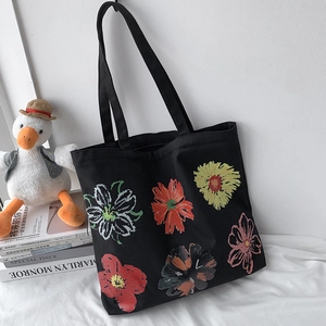 Detail of black canvas tote bag with hand-painted colorful flower illustrations
