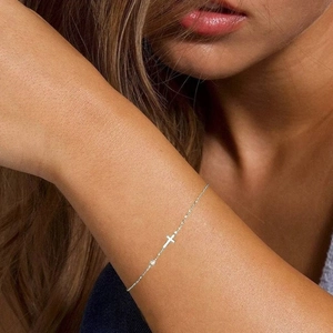 Close-up of a minimalist S925 silver cross bracelet with a small diamond on the wrist