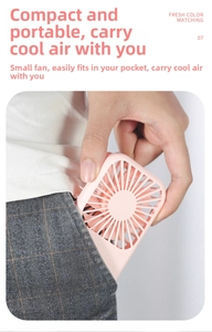 Pink mini portable fan being placed into a small pocket showing its compact size