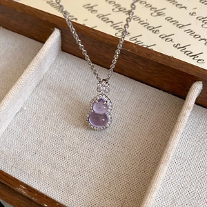 Macro shot of purple gourd pendant necklace with white zircons in a wooden jewelry box