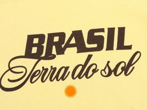 Dettaglio del tessuto in cotone giallo con stampa grafica Brasil e sole marrone